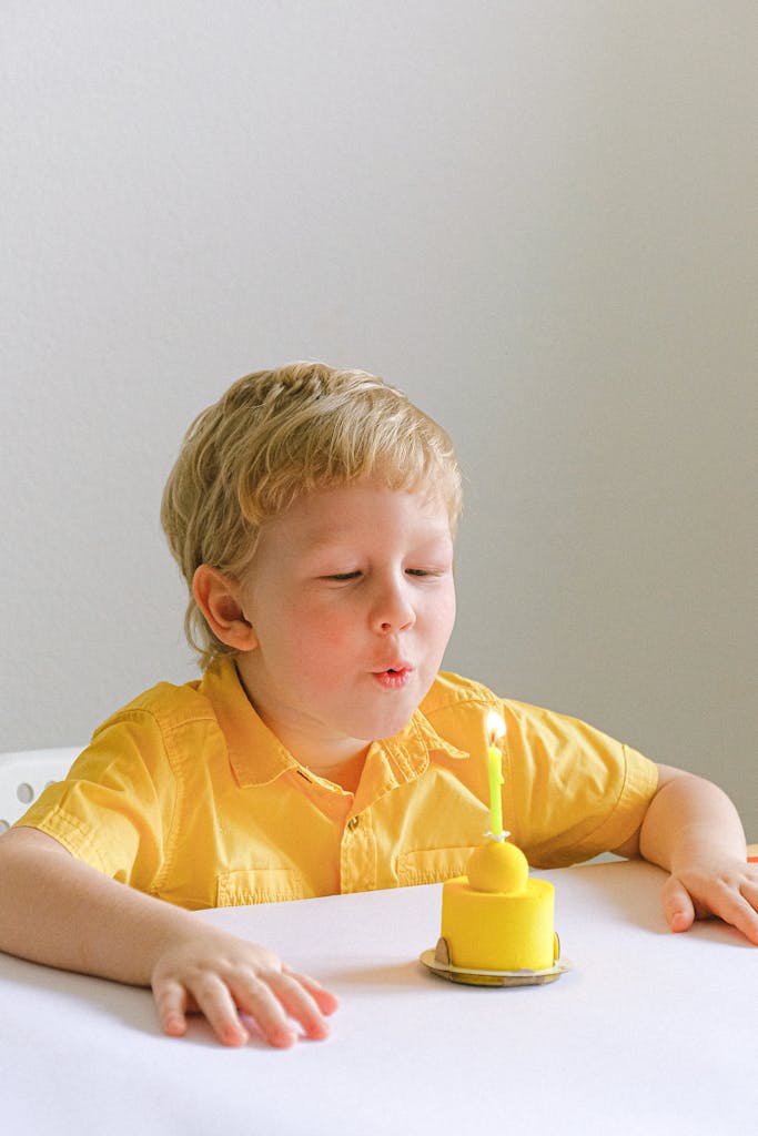 Boy In Yellow Polo Blowing A Candle